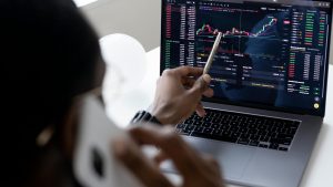 Man talking on the phone and looking at investments on a laptop